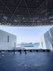 View of modern architecture at Louvre Abu Dhabi with city skyline in the background.