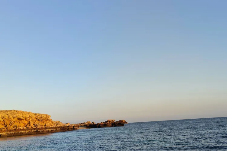 Rocky coastline of Muscat at sunset with a clear sky.