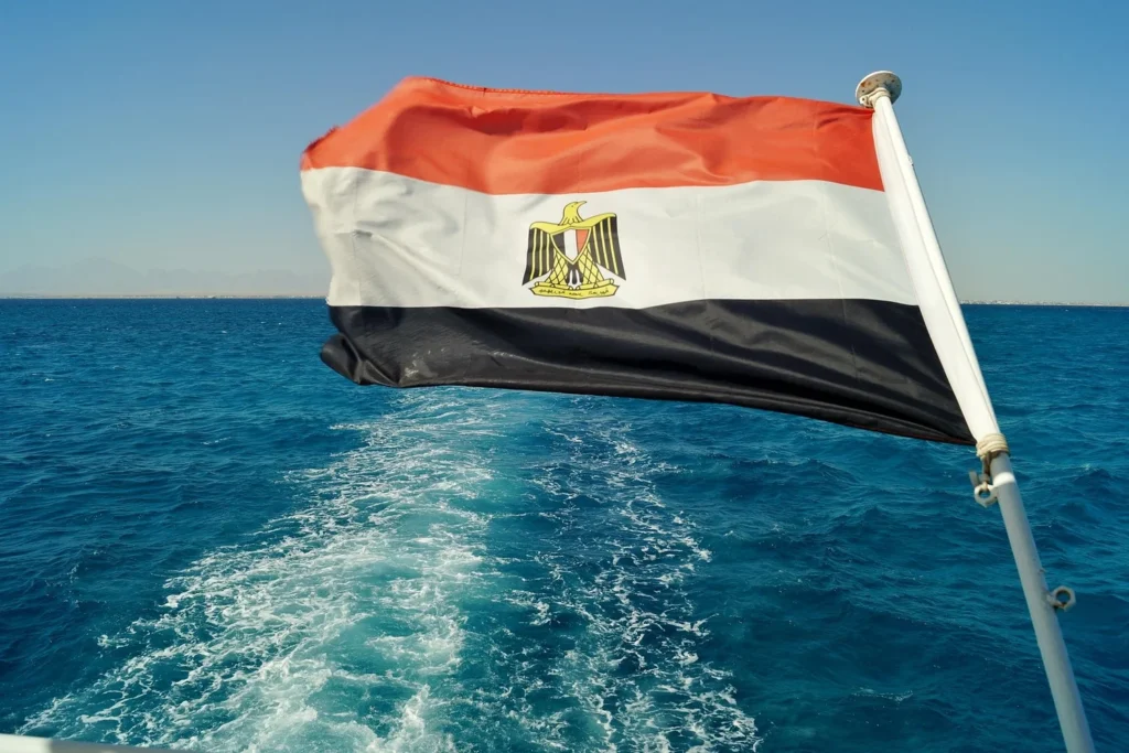 Egyptian flag on a boat with a view of the sea and distant mountains.