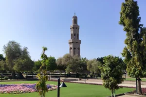 The minaret of the Grand Mosque in Muscat with surrounding gardens and trees.