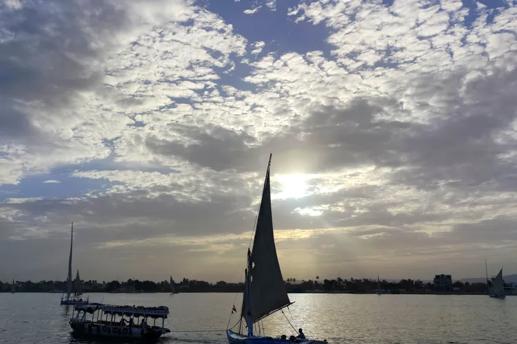 A felucca sailing on the Nile River at sunset in Luxor, Egypt.