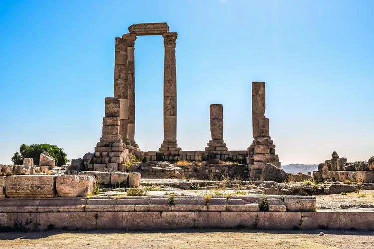 Ancient columns of the Temple of Hercules in Amman under a clear blue sky.