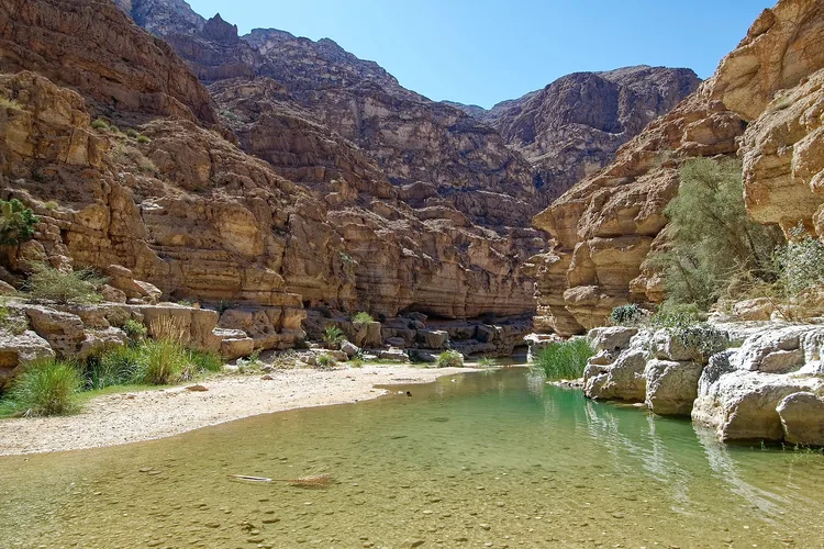 Rocky landscape of Wadi Shab in Oman with clear water pools.