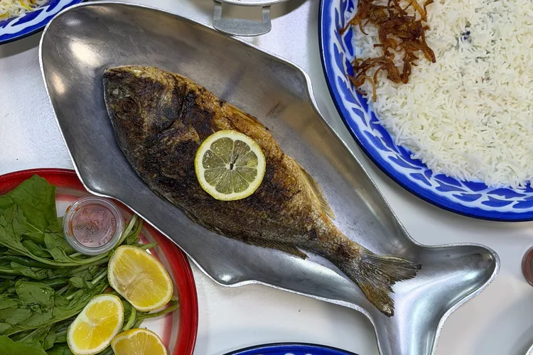 Grilled fish with lemon slice served on a metal plate in Oman.