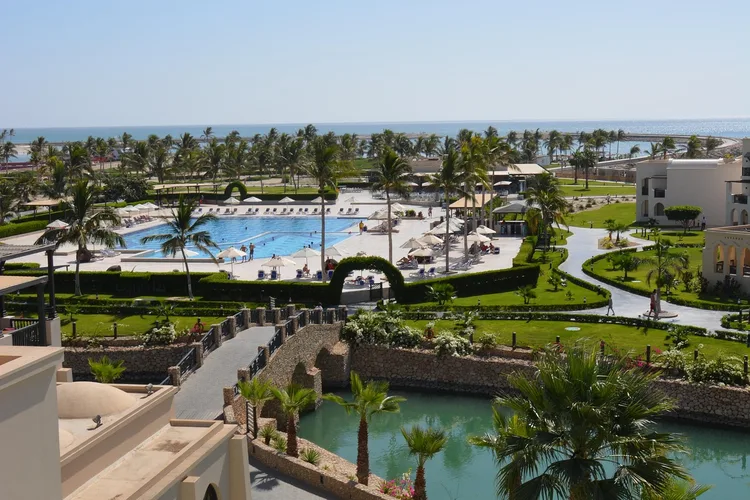 View of a luxury resort with pool and gardens in Oman, near the coastline.