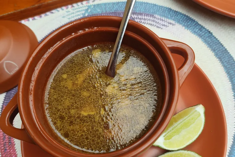 Omani lentil soup served in a brown clay bowl with lime wedges.