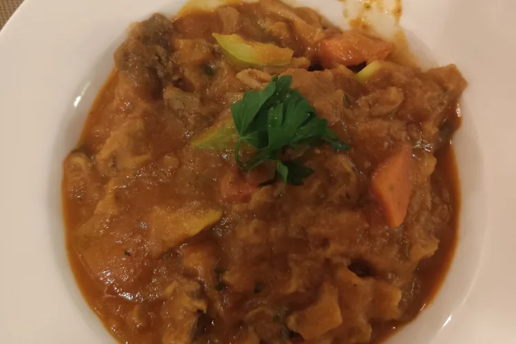 Thareed dish with vegetables and meat in a white bowl.