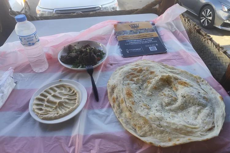 Traditional Omani breakfast with bread, salad, and hummus at Ghamdan in Muscat.