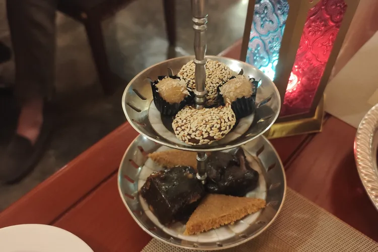 Assorted traditional Omani desserts on a tiered stand with colorful lantern.