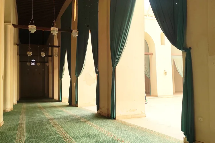 Interior view of Al-Hakim Mosque with green carpets and curtains in Cairo, Egypt.