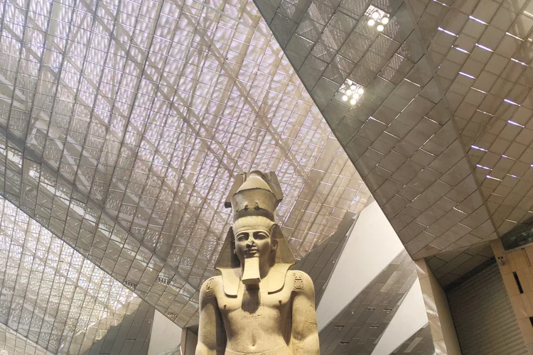 Interior view of the Grand Egyptian Museum with a large ancient statue.